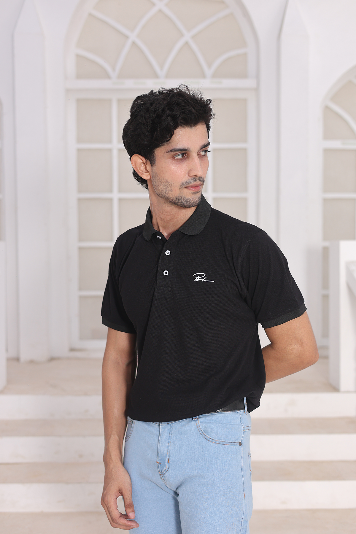 Black polo shirt with short sleeves and embroidered chest logo, side view
