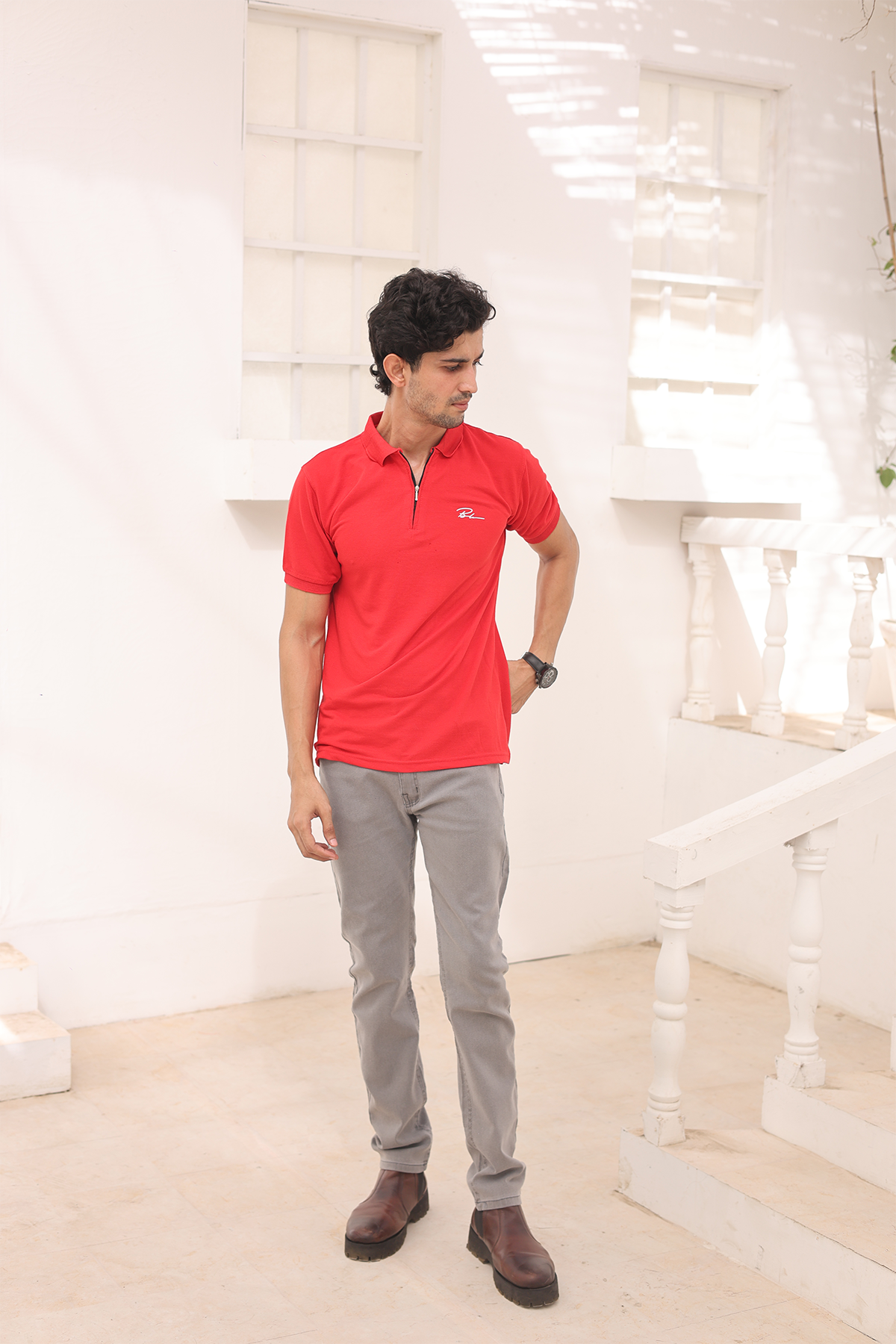 Red polo shirt with short sleeves and chest logo, worn with gray pants.