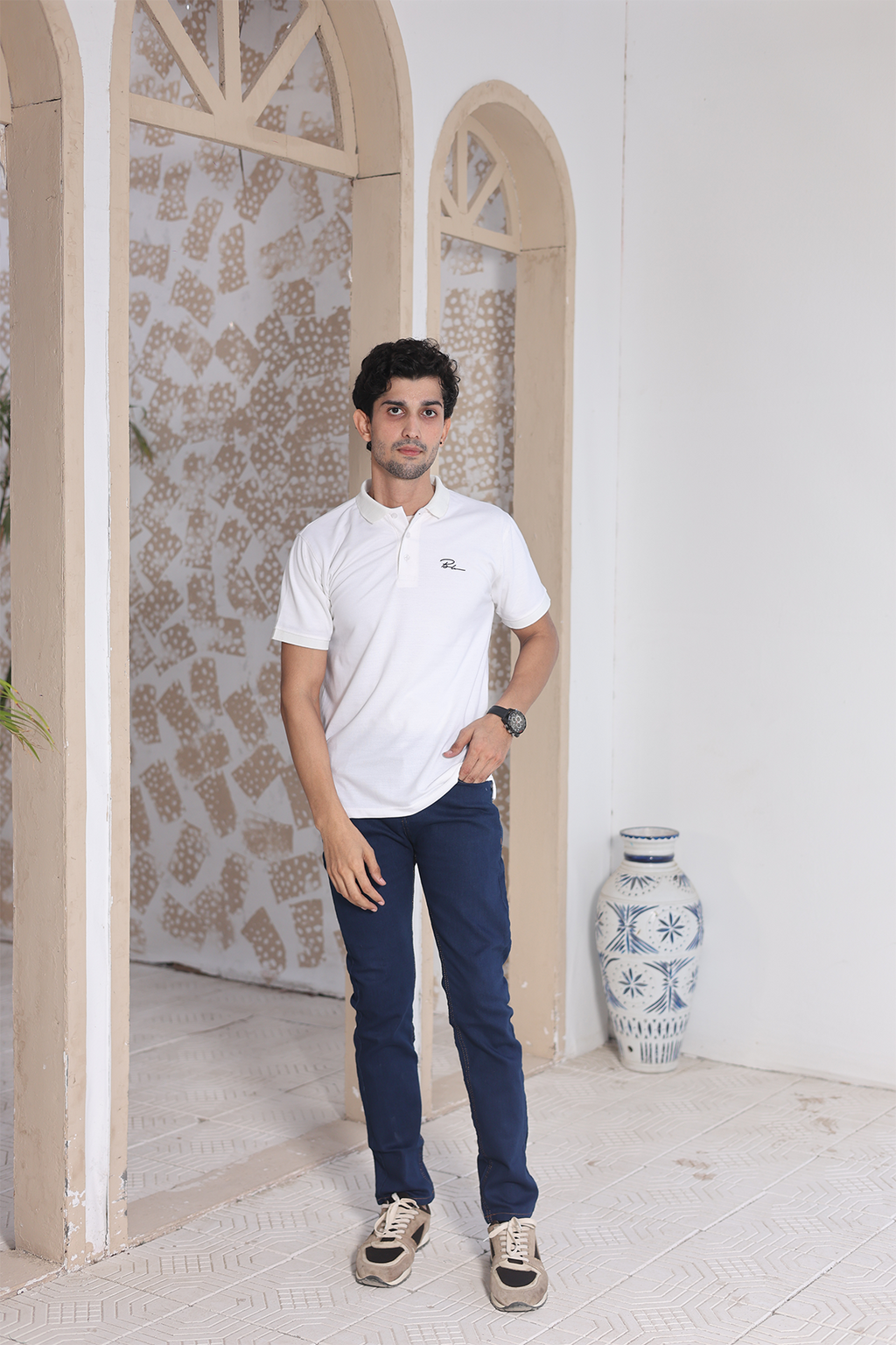Men's white polo shirt with buttoned collar and chest logo, model wearing it