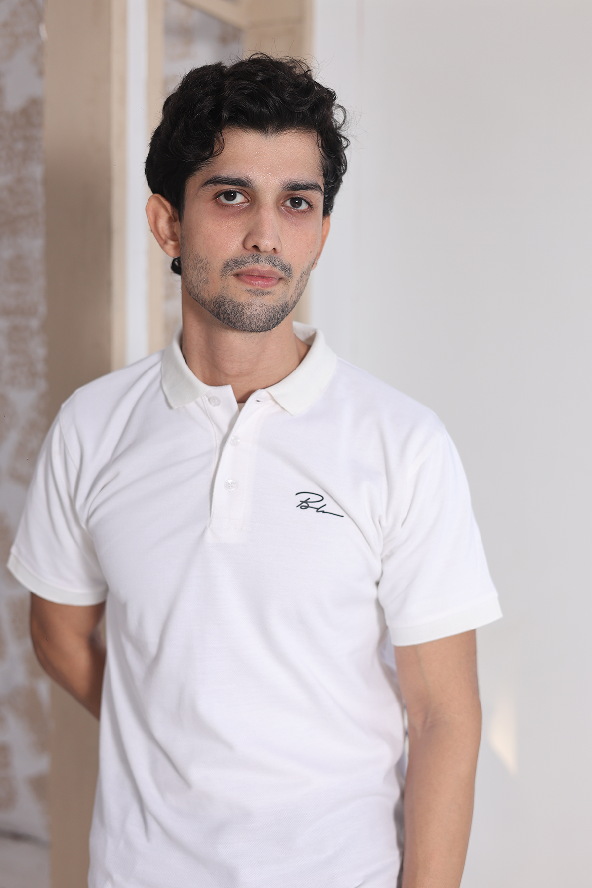 Men's white polo shirt with buttoned collar, small chest logo, and short sleeves